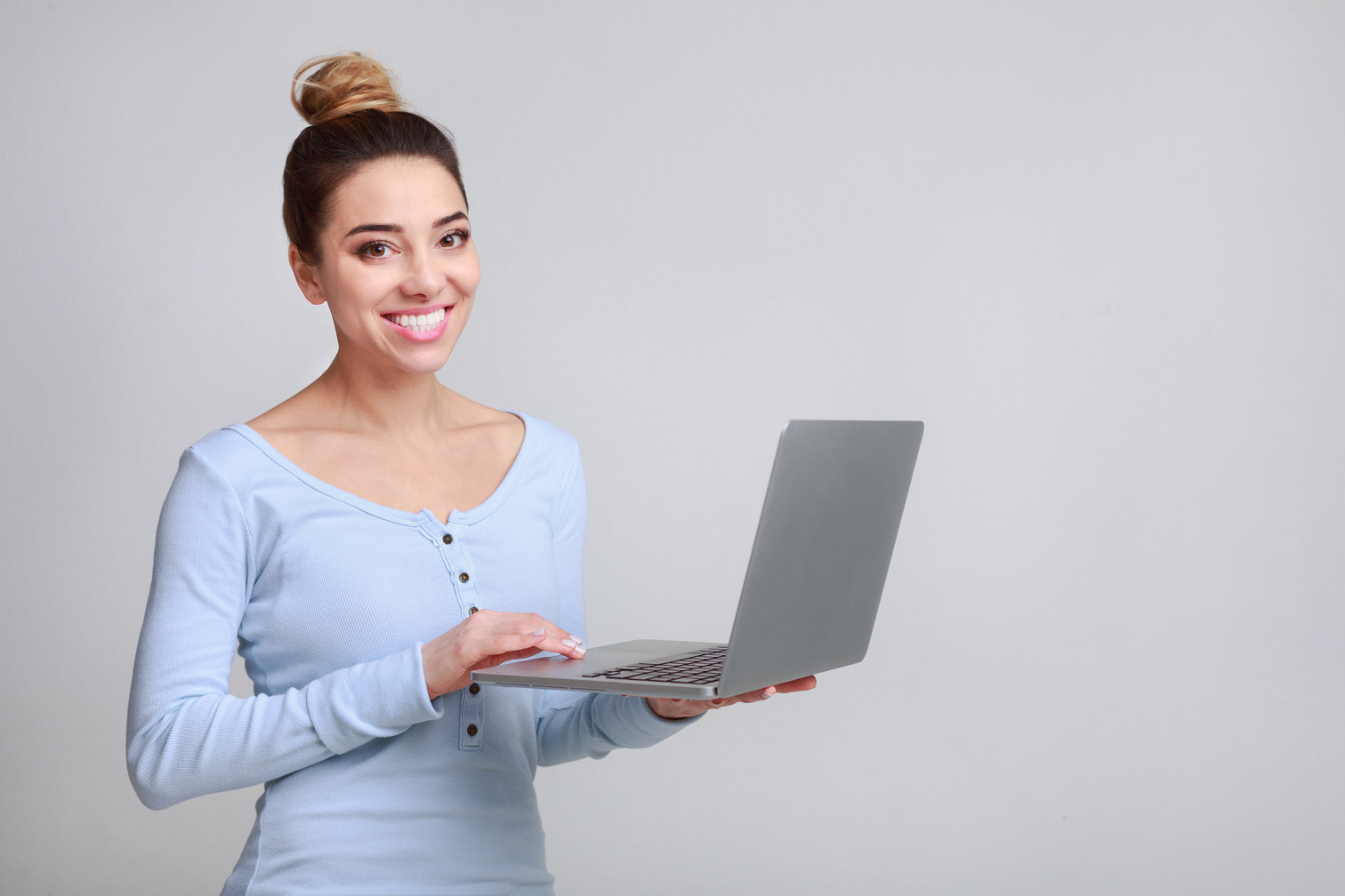 Happy woman holding personal computer posing on camera